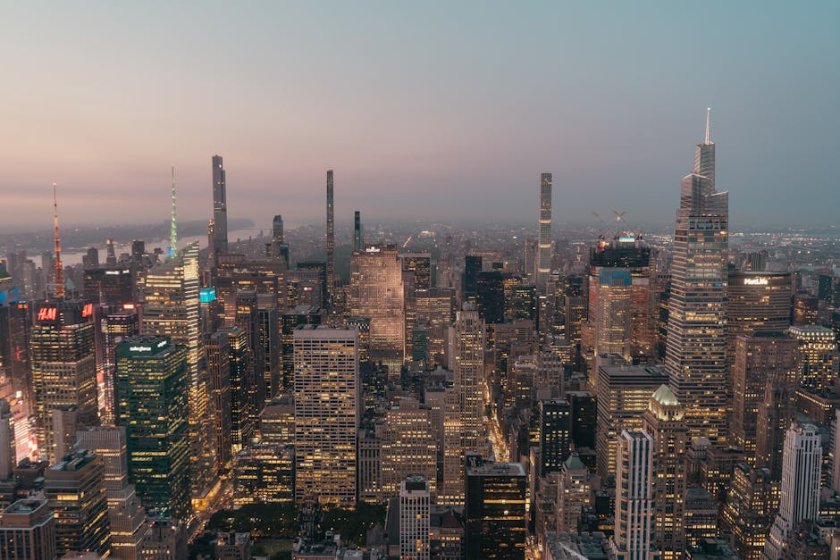 Stunning aerial view of illuminated New York City skyline at dusk showcasing skyscrapers.