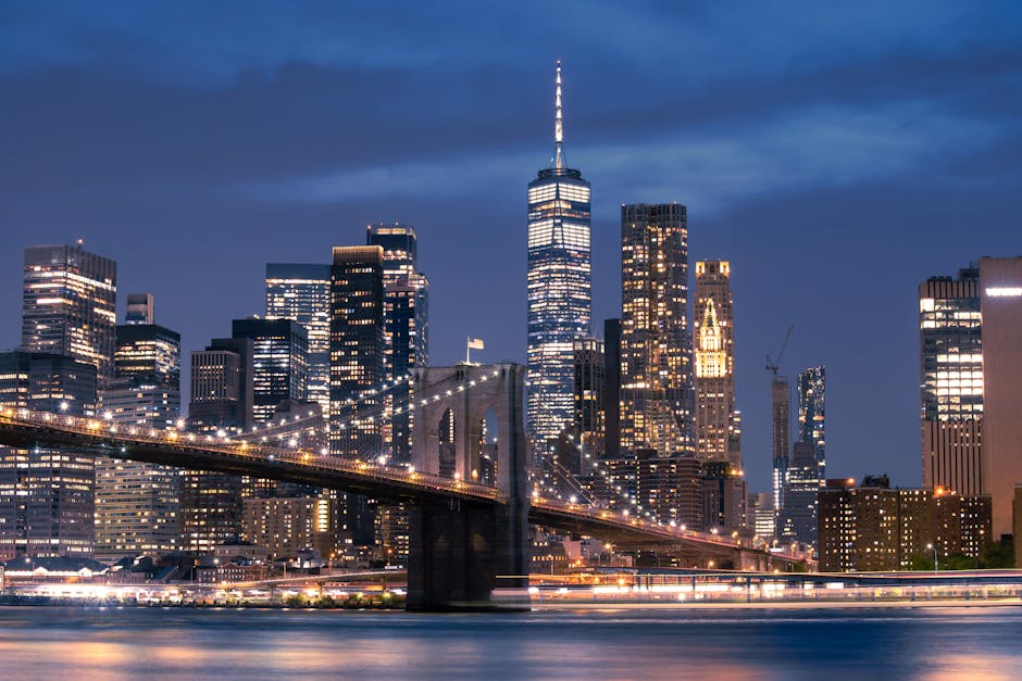 Stunning view of the Brooklyn Bridge and New York City skyline at dusk, with glowing city lights.
