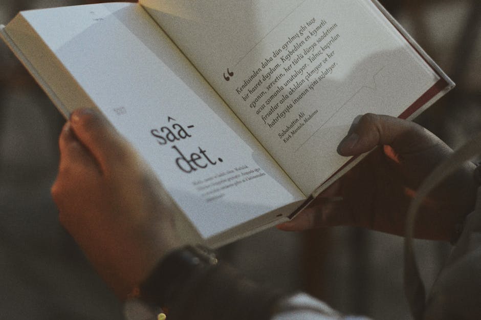 Person holding and reading an open book with visible text.