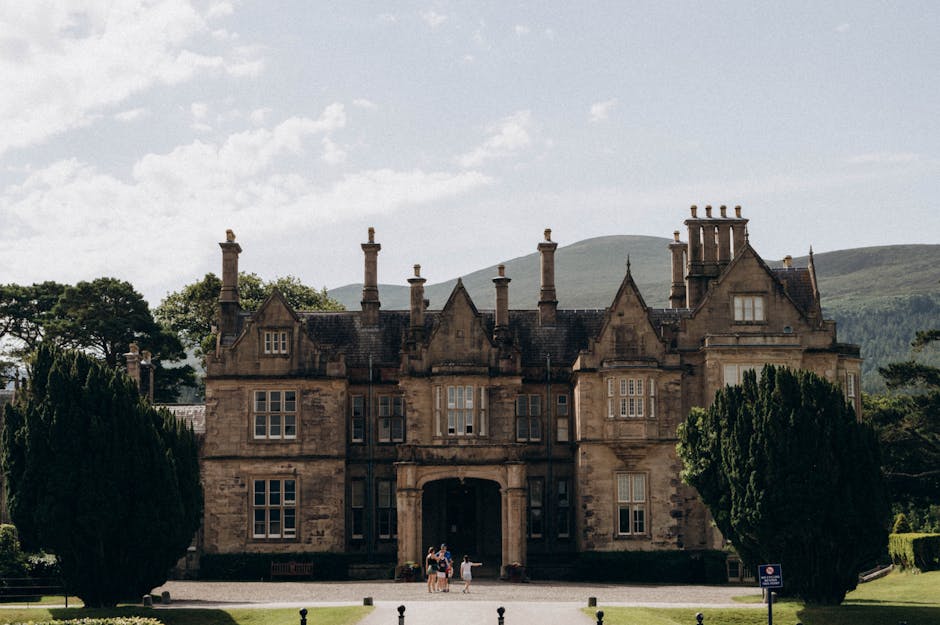 Exterior view of the historic Muckross House in Killarney, Ireland, surrounded by greenery.